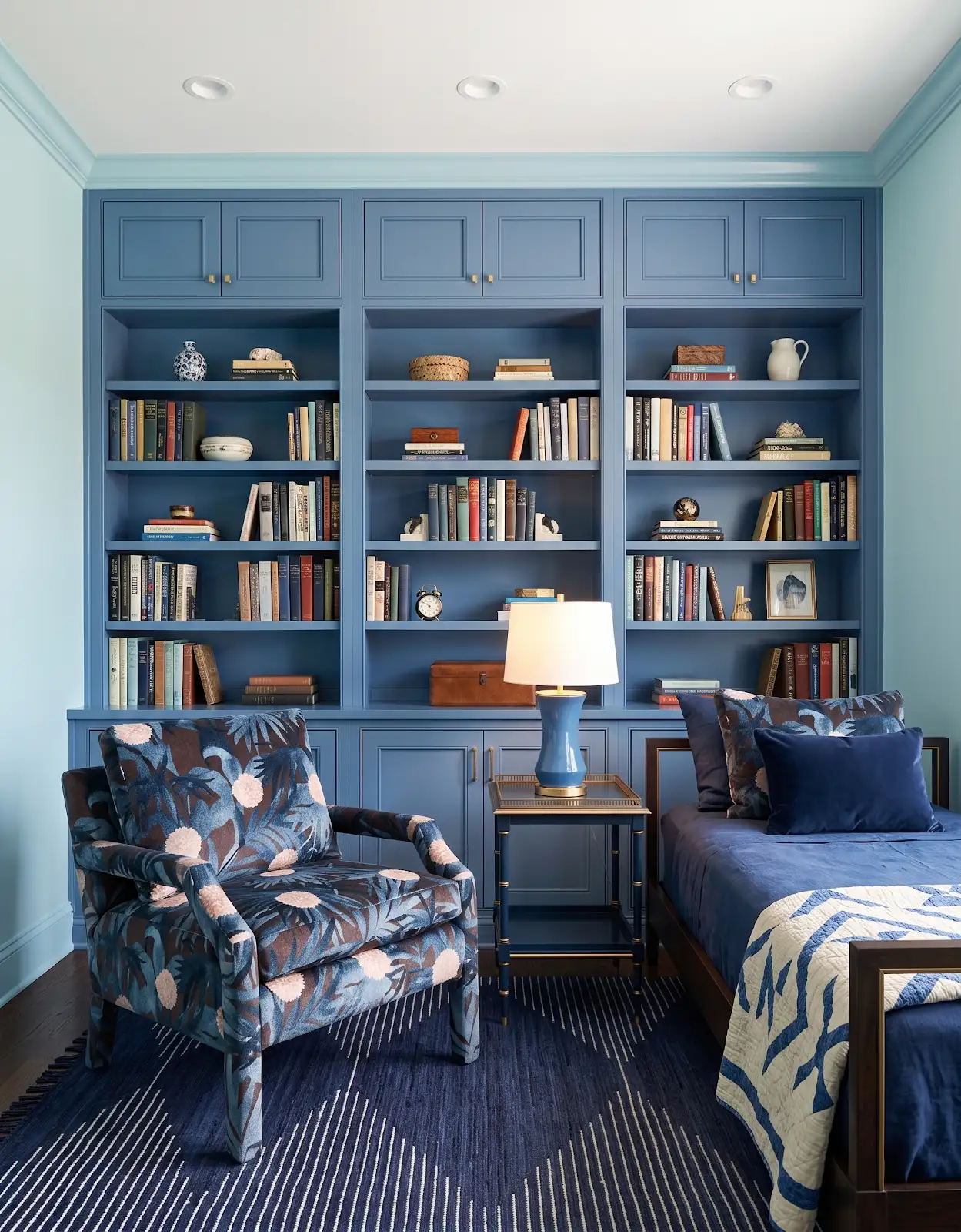 AI-generated room concept with blue bookshelves, a chair, table lamp and patterned textiles